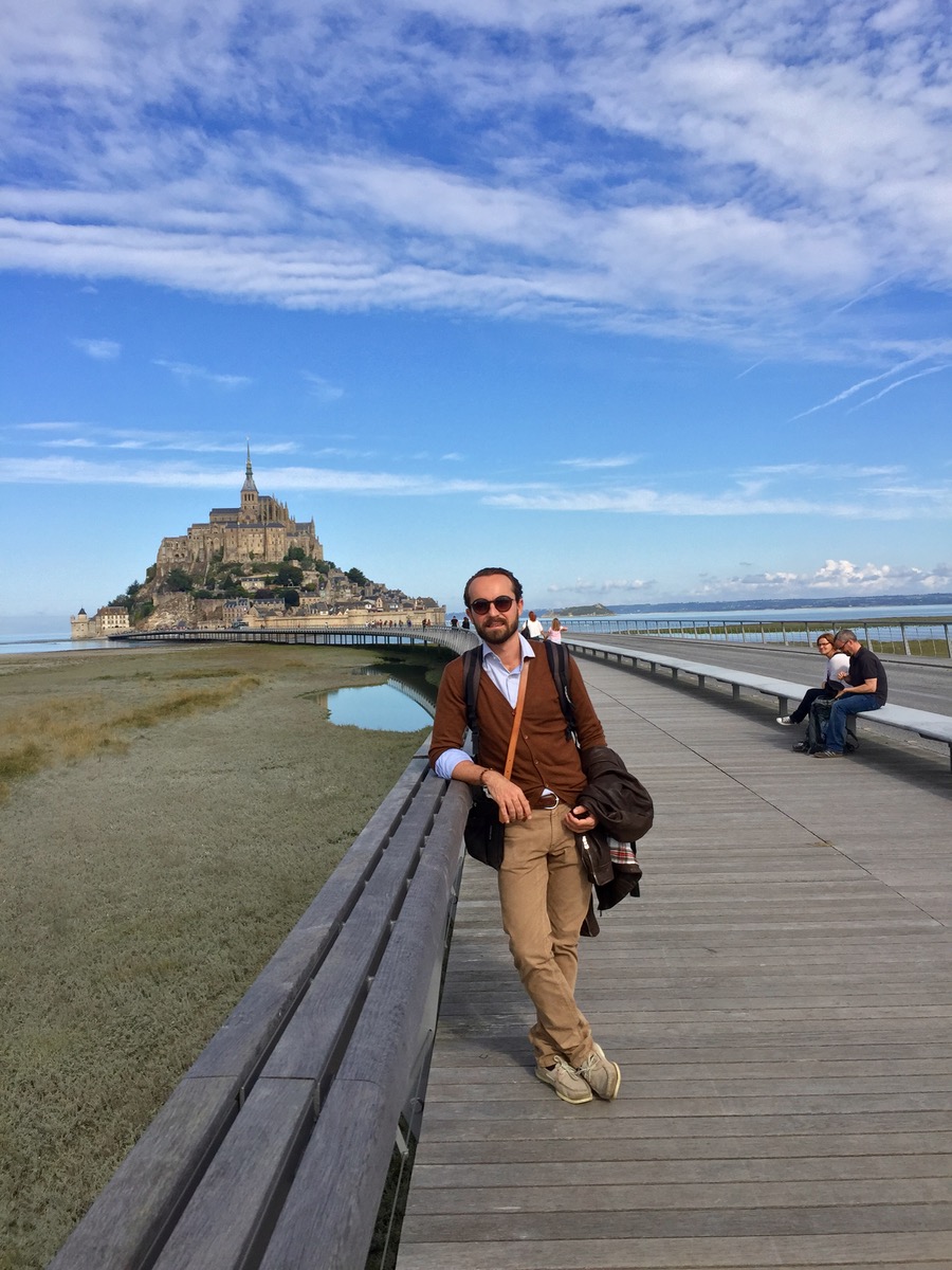 Cute French husband in front of Le Mont-Saint-Michel, a rocky island in Normandy, France.